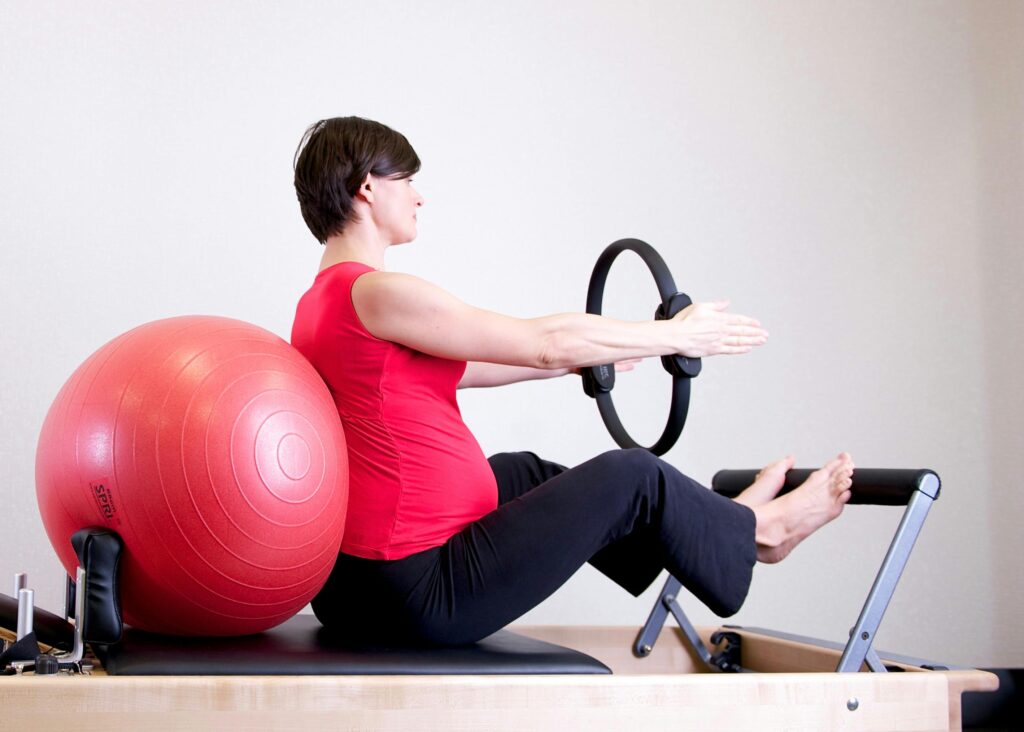 donna incinta che esegue un esercizio di Pilates su Reformer